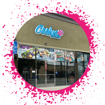 Tan storefront with a light blue sign that says 'Cookie' with a pink electrical plug with decals of large, thick cookies in the window that has the address of 3060