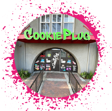 Neon green sign that says 'cookie plug' that's on a gray and red building with graffiti stickers on the door and windows