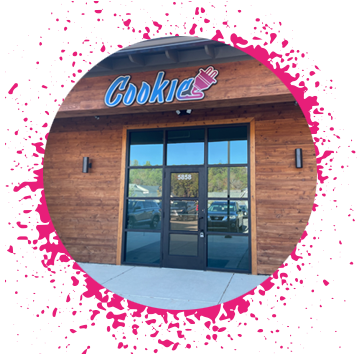 wooden building with large black glass windows and doors with a big blue sign that says 'cookie' with a pink electrical plug attached to it.